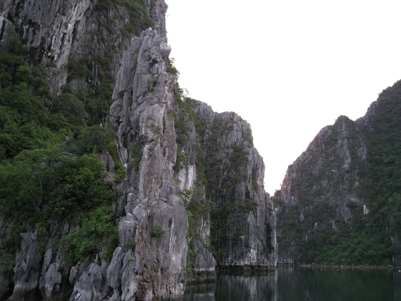 Steep limestone karsts rise from calm waters in Bai Tu Long Bay.