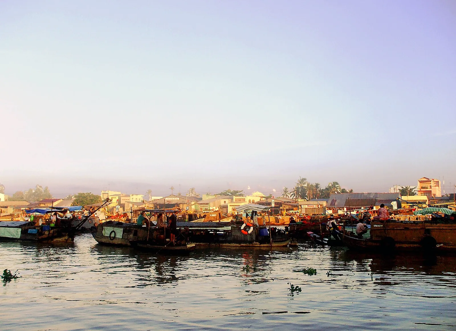 Wooden boats gather on the water at Cai Rang floating market in Can Tho at dusk.