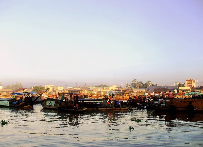 Wooden boats gather on the water at Cai Rang floating market in Can Tho at dusk.