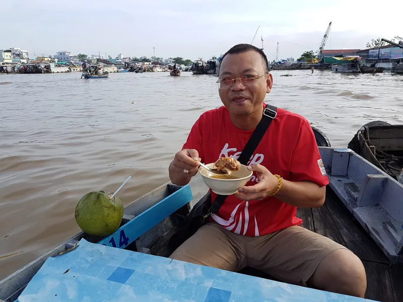 A man eats a bowl of noodle soup on a small boat at Cai Rang floating market in Can Tho.