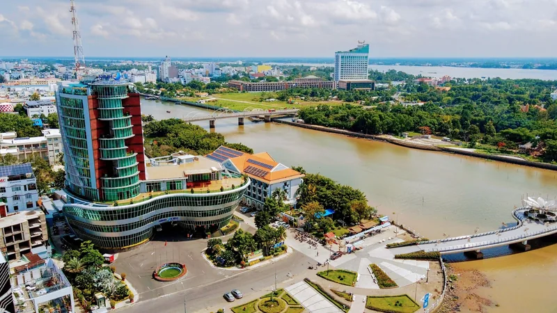 Aerial view of Can Tho city skyline along the Hau River with modern buildings and bridges under a bright sky.