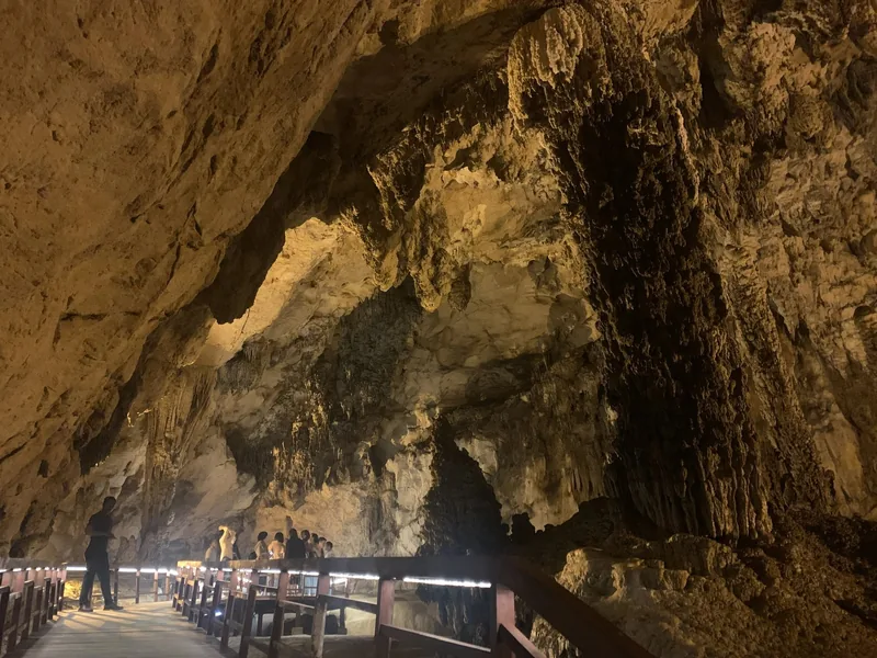 Visitors walk along a lit wooden walkway inside a large limestone cave near Ban Gioc, Cao Bang.