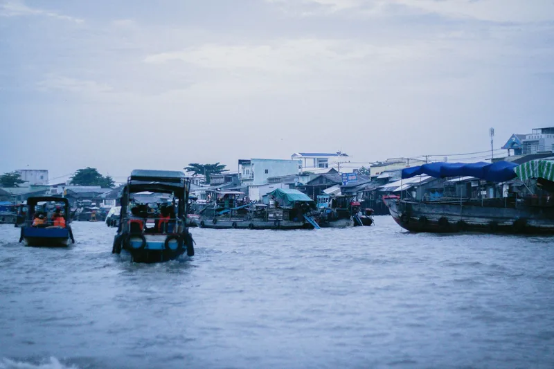 Passenger boats and cargo vessels gather at a bustling floating market on a river in Vietnam.