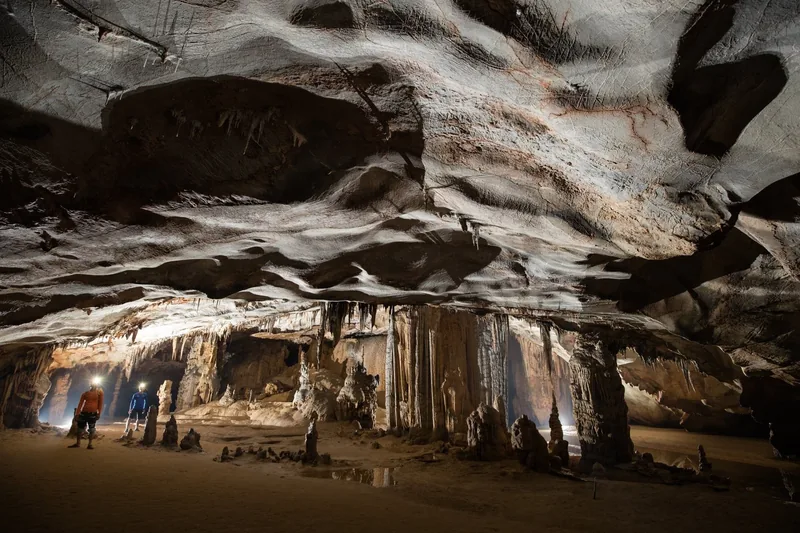 Explorers with headlamps walk through the vast stalactite chamber of Paradise Cave in central Vietnam.