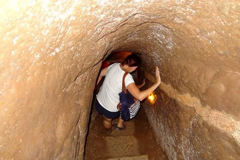 A visitor crouches while walking through the narrow underground passage of the Vinh Moc tunnels near Hue.