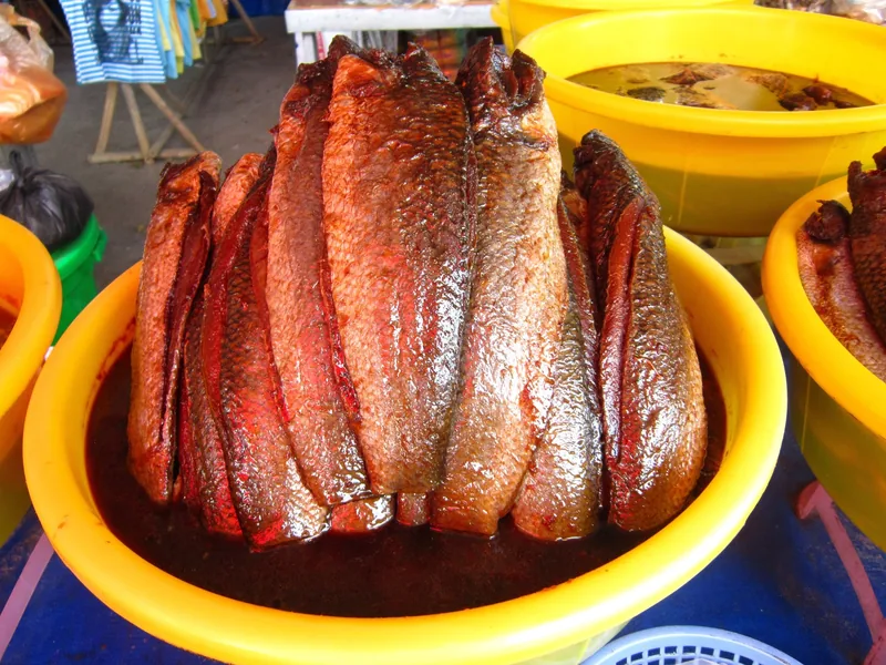 Salted fish fillets stacked in a yellow basin at a market in Chau Doc.