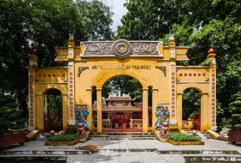 Yellow arched gate of a temple honoring the Hung Kings stands among trees in a Ho Chi Minh City park.