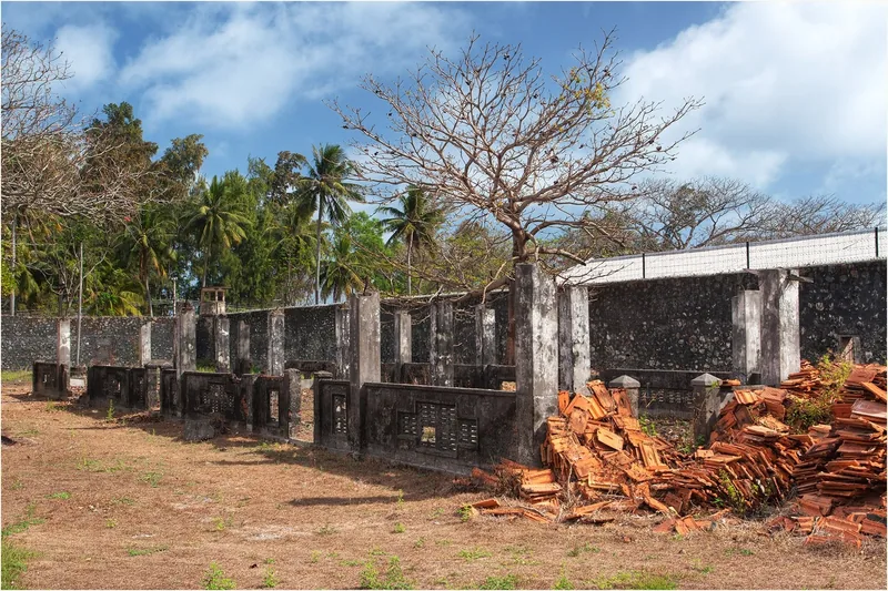 Ruined walls and stacked roof tiles at the old Phu Tuong prison compound in Con Dao, Vietnam.