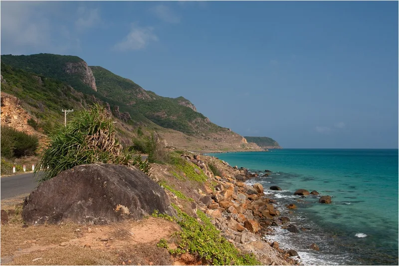 A coastal road winds along rocky cliffs above turquoise waters near Con Dao.