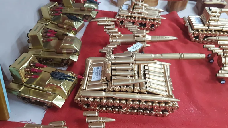 Handmade tank models crafted from bullet casings displayed on a red cloth near the Cu Chi Tunnels.