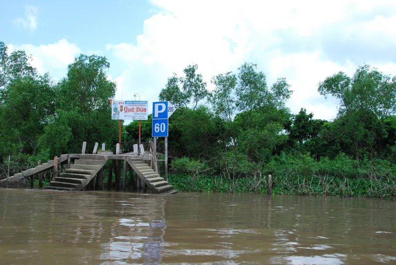 A concrete jetty with a parking sign leads into muddy Mekong Delta waters near Ben Tre, Vietnam.