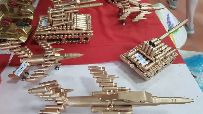 Handmade tanks and jets crafted from bullet casings displayed on a red-covered table near the Cu Chi tunnels.