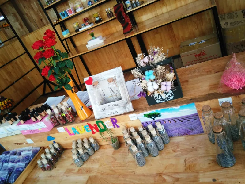 A souvenir shop counter in Da Lat displays bottled lavender, dried flower arrangements, and red roses for sale.