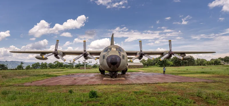A retired military transport plane sits on display at Khe Sanh Combat Base under a blue sky with clouds.