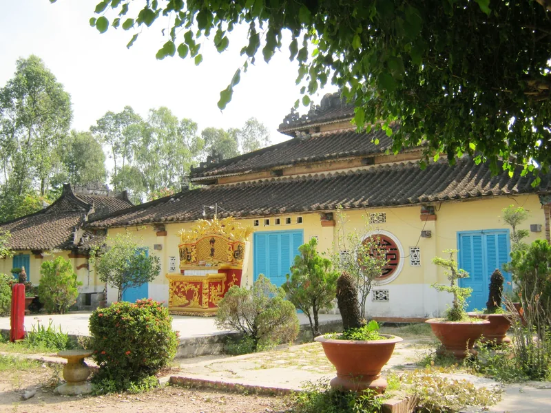 A traditional yellow communal house with tiled roof and blue shutters at Dinh Yen village, Dong Thap province.