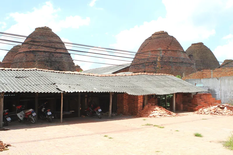 Dome-shaped brick kilns rise behind a tin-roofed workshop with motorbikes parked in Dong Thap.
