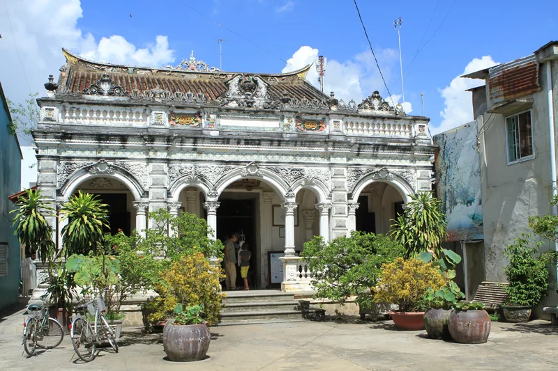 An ornate colonial-style building with arched columns and potted plants in Dong Thap, Vietnam.