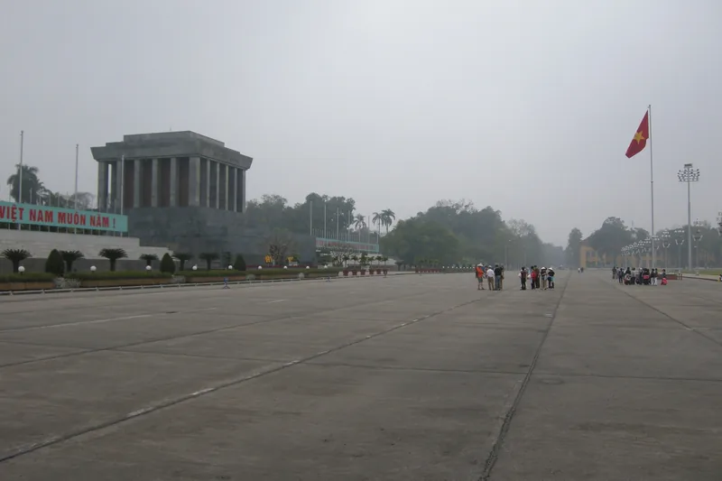 Ho Chi Minh Mausoleum stands beside the Vietnamese flag across the vast paved expanse of Ba Dinh Square in Hanoi.