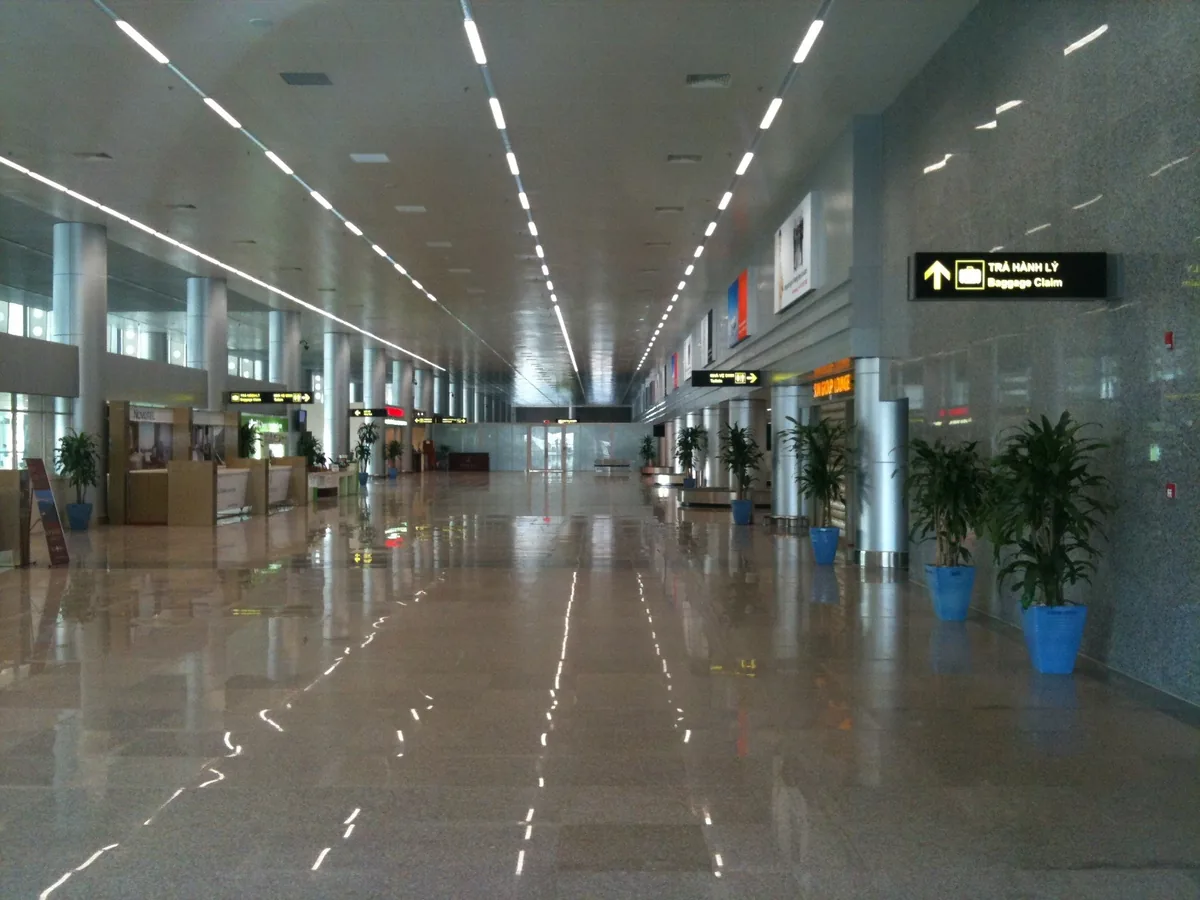An empty terminal hallway with signage for baggage claim at Da Nang International Airport.
