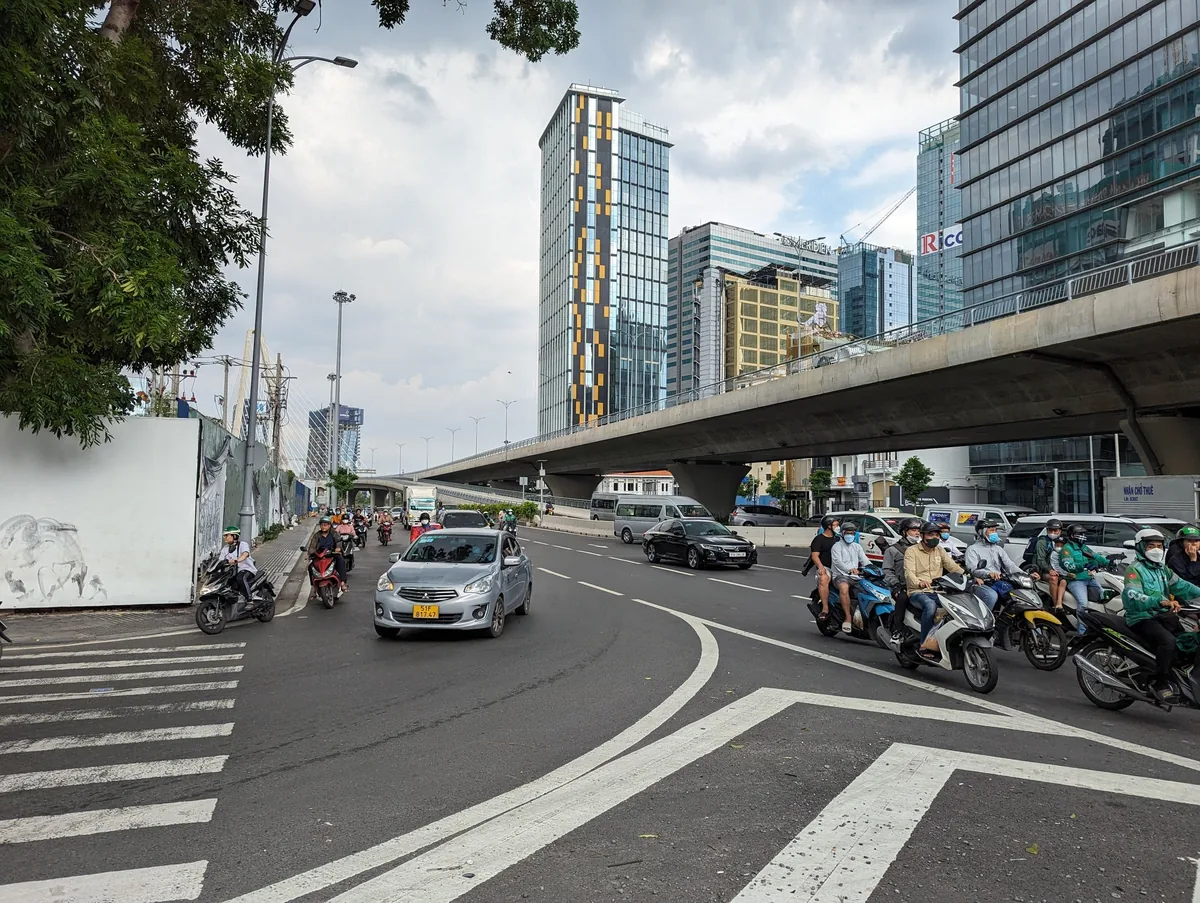 Traffic of cars and motorbikes flows past high-rise buildings on a busy boulevard in Ho Chi Minh City.
