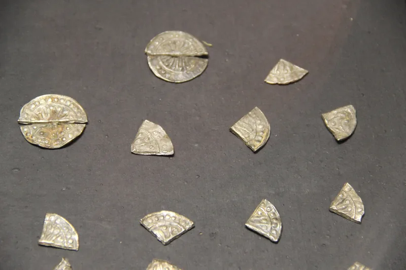 Fragmented ancient silver coins from Oc Eo culture displayed on a dark surface in a Ho Chi Minh City museum.