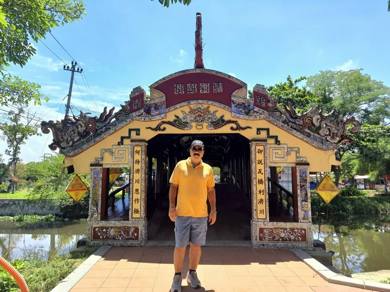 A tourist stands before the ornate tiled roof and Chinese inscriptions of Thanh Toan Bridge near Hue.