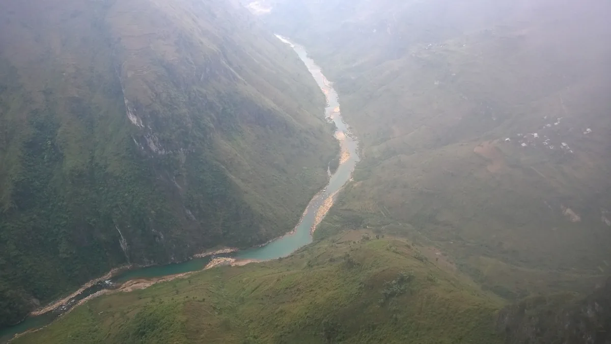 A turquoise river winds through deep misty canyons near the Ma Pi Leng Pass in Ha Giang.