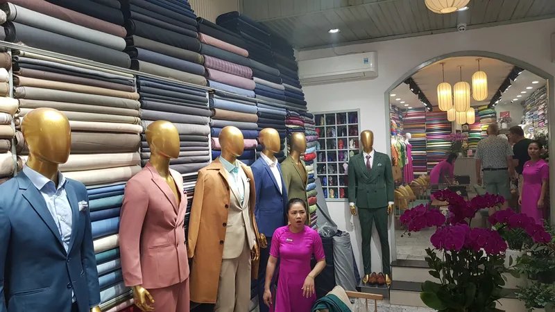 Mannequins in tailored suits and stacked fabric rolls fill a tailor shop in Hoi An.