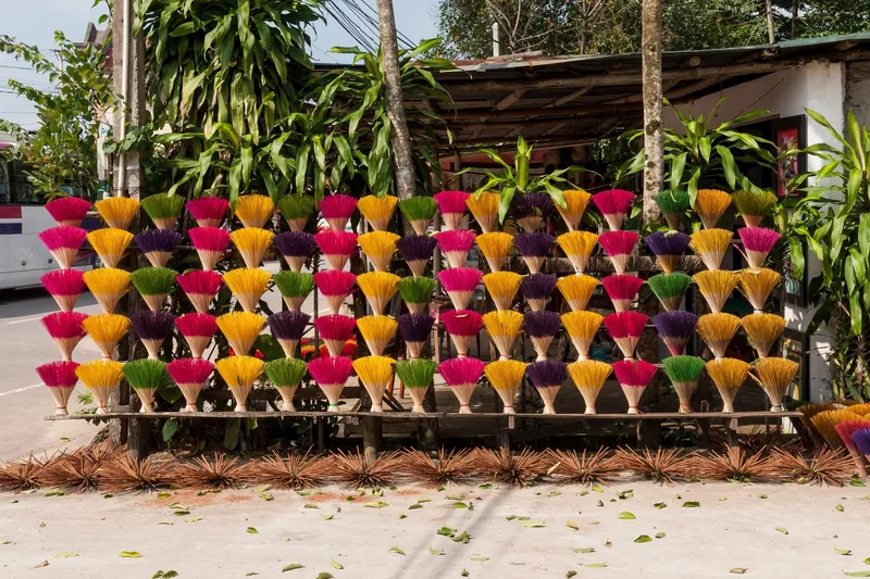 Bundles of colorful dyed incense sticks fan out on display racks near a tomb site in Hue, Vietnam.