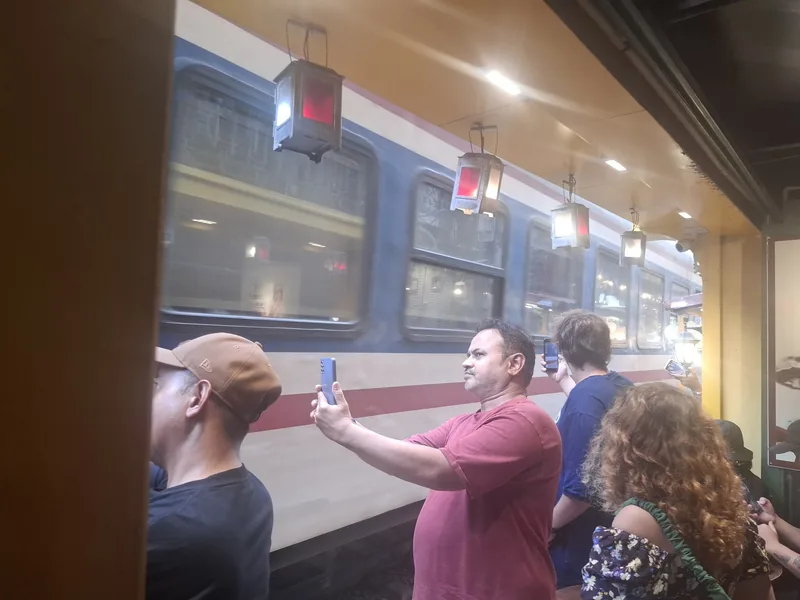 Tourists photograph a passing train from a narrow café passage in Hanoi's famous Train Street.