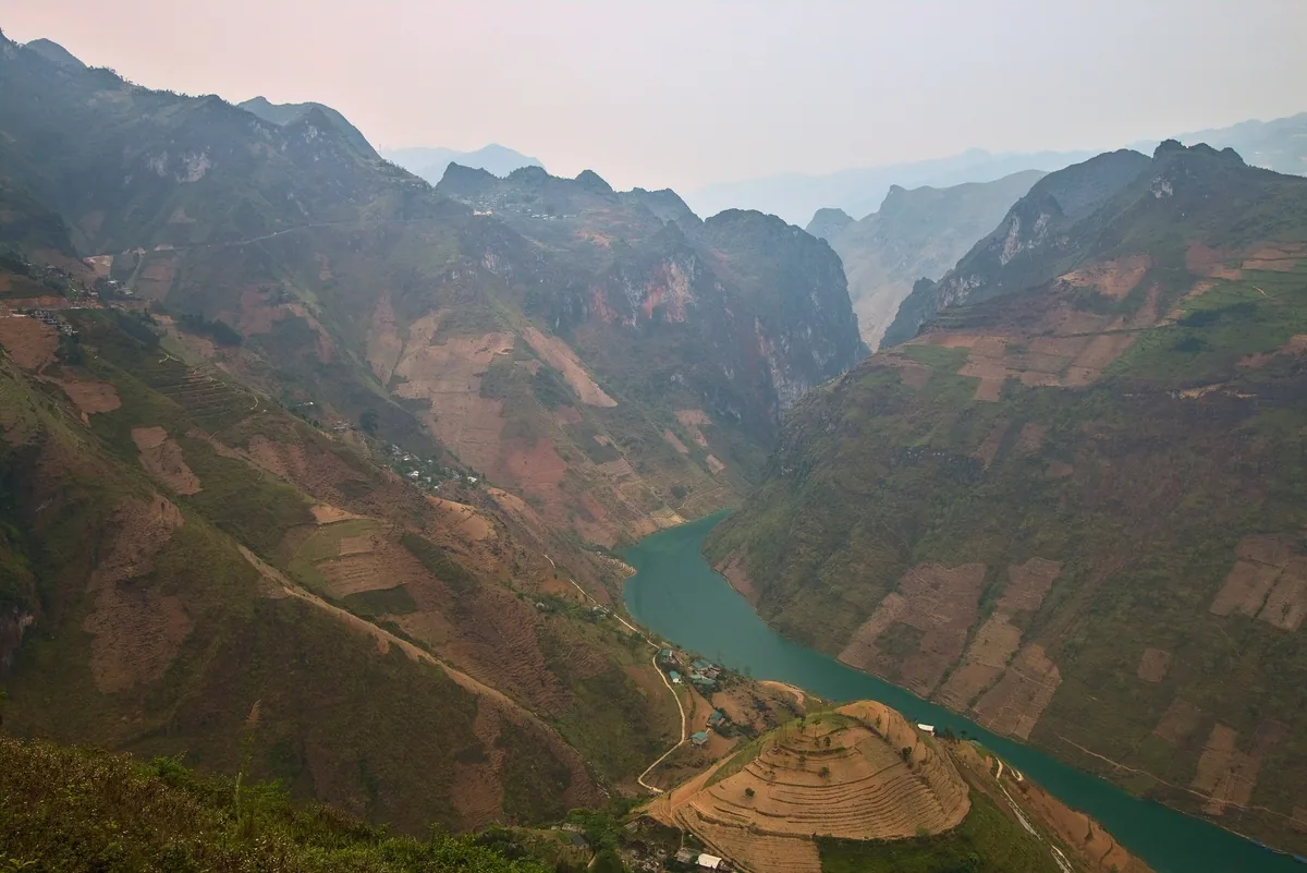A turquoise river winds through terraced mountains in the dramatic Ha Giang landscape of northern Vietnam.