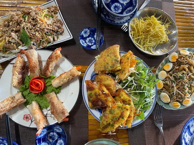A Vietnamese feast of crispy shrimp spring rolls, banh xeo pancakes, salad, and stir-fried dishes on a table.