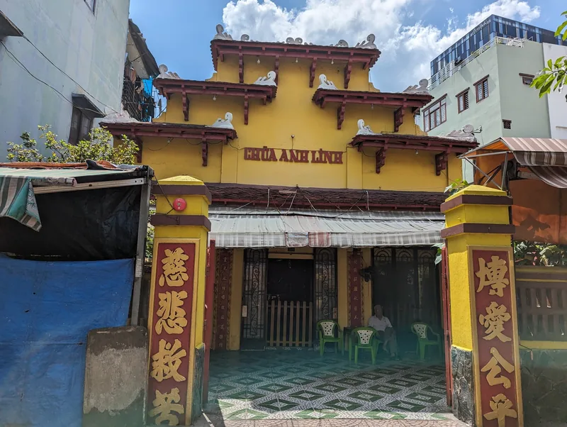 Yellow facade of Chua Anh Linh temple with red Chinese-script pillars in Ho Chi Minh City.