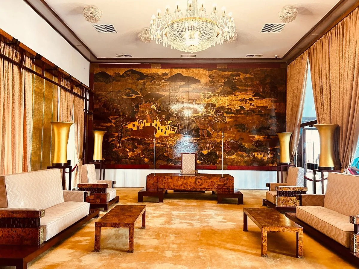 Grand reception room in Ho Chi Minh City with lacquer mural, crystal chandeliers, and vintage sofas.
