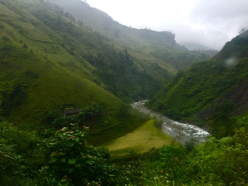 A river winds through a misty green valley with terraced fields near Bao Lac, Cao Bang.