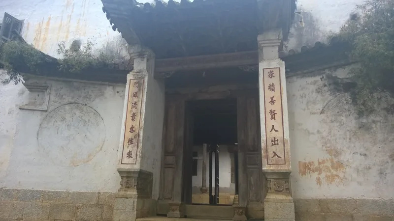 Weathered gateway with Chinese couplets carved on stone pillars at the Hmong King's Palace in Ha Giang.