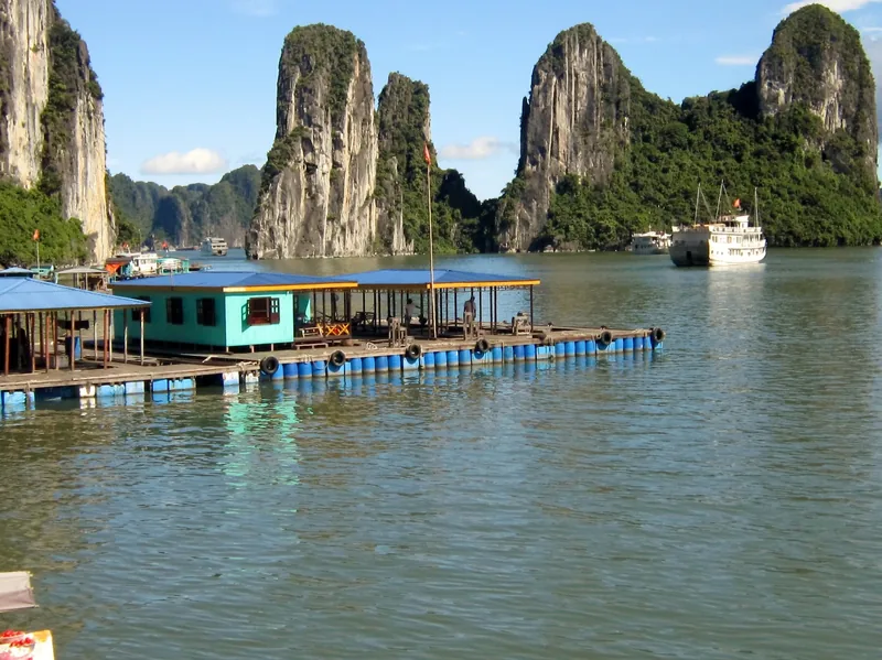 A floating pontoon house sits among limestone karsts in Ha Long Bay, Vietnam.