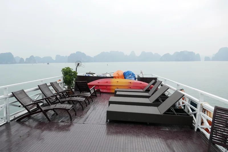 Sun loungers and kayaks on a cruise ship's sundeck overlooking the limestone karsts of Ha Long Bay