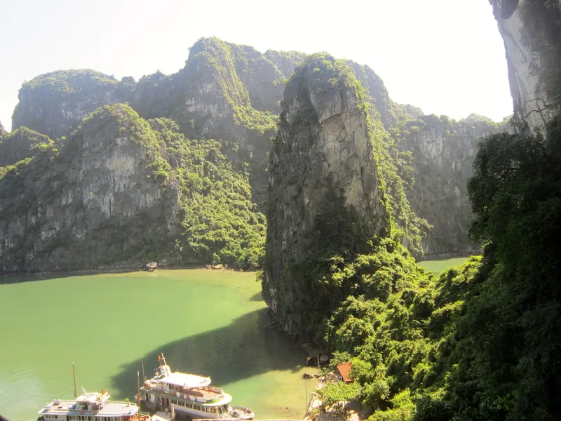 Limestone karsts rise above emerald water with cruise boats anchored below in Ha Long Bay.