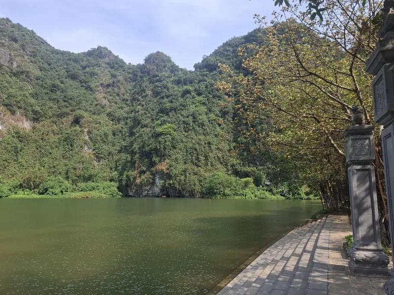 Limestone karst mountains rise beside a still river with a stone path in Ninh Binh, Vietnam.