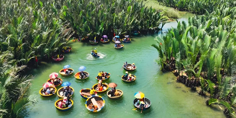 Aerial view of round basket boats with tourists floating among the coconut palm water canals of Cam Thanh, Hoi An.