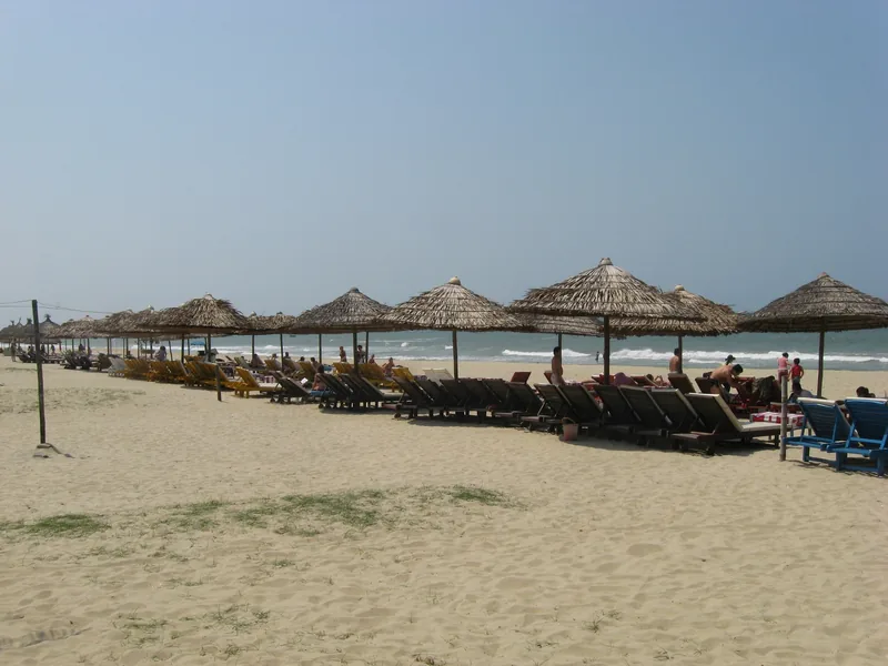 Rows of thatched parasols and sun loungers line the sandy shore at Cua Dai Beach in Hoi An.