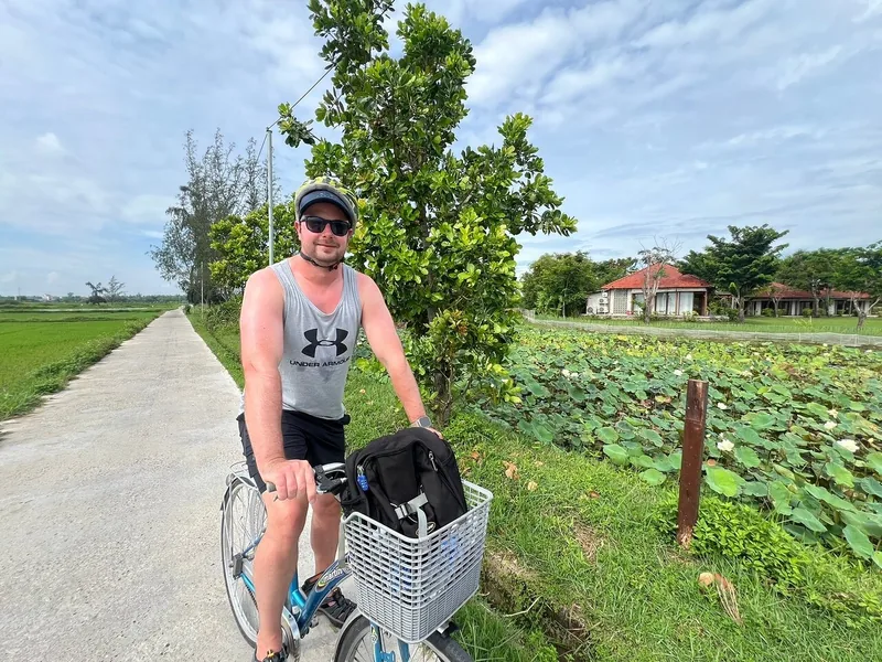 A cyclist pauses on a countryside path beside lotus ponds near Trà Quế vegetable village in Hoi An.
