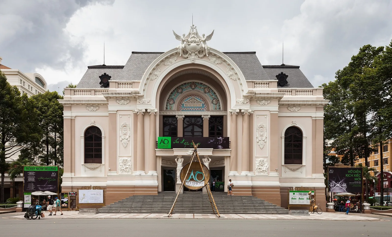 French colonial facade of the Saigon Opera House in Ho Chi Minh City under a cloudy sky.