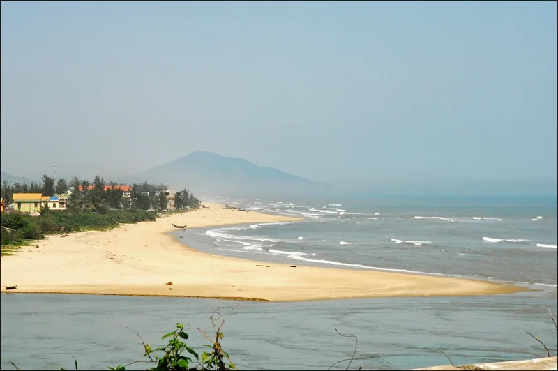 A sandy beach curves along the coast near Lang Co fishing village, with hazy mountains in the background near Da Nang.
