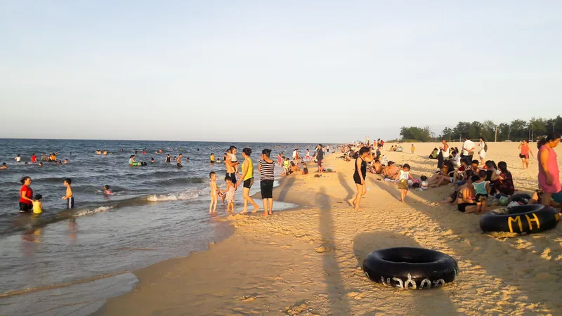 Crowds of visitors relax and swim in the shallow waves at Thuan An Beach near Hue in the late afternoon.