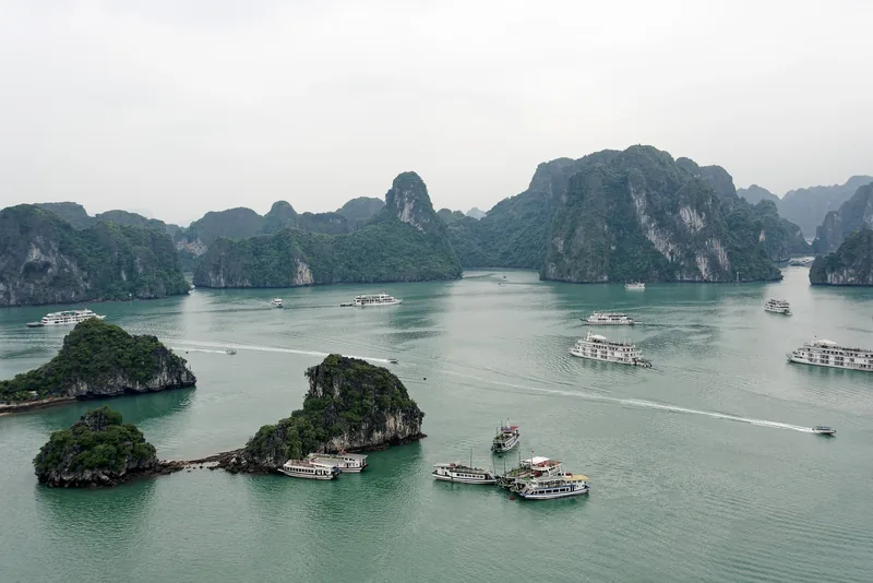Cruise boats sail among limestone karsts and islets in Ha Long Bay, seen from Titov Island.