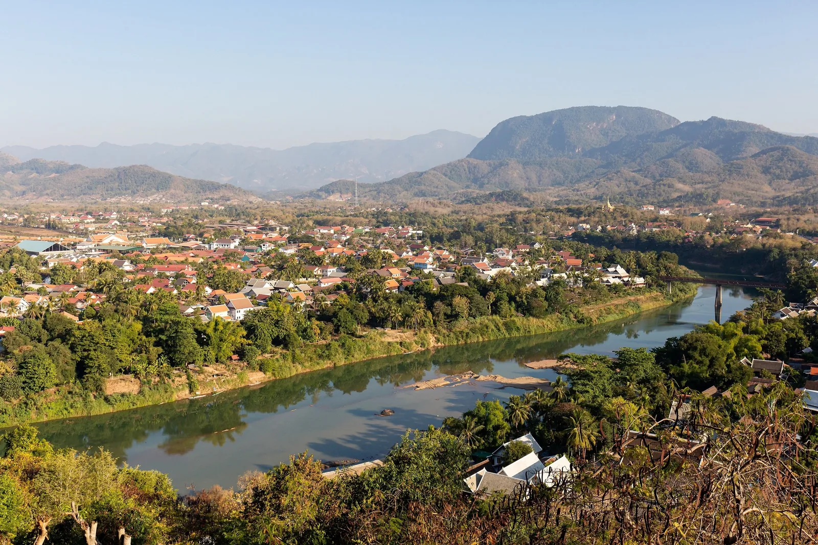 Aerial view of Luang Prabang town along the Nam Khan River, surrounded by mountains, seen from Mount Phousi.