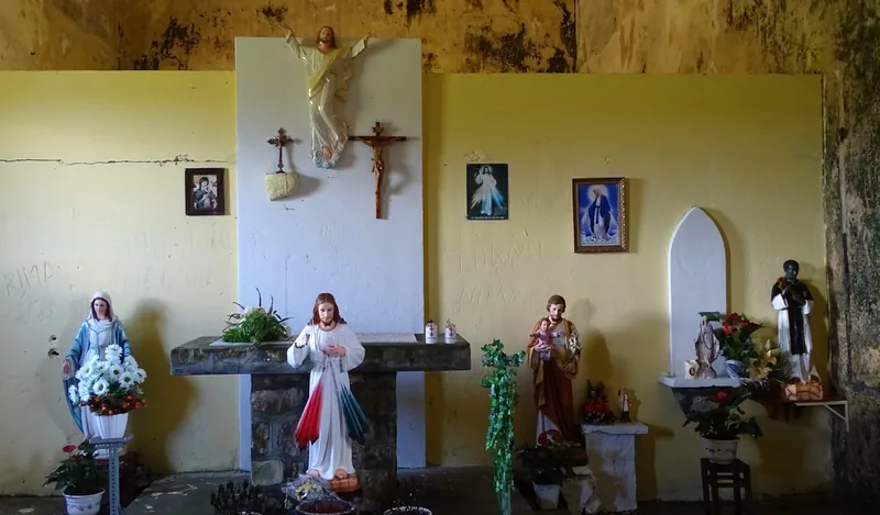 Weathered altar with religious statues, crucifix and paintings inside an old Roman Catholic church in Kampot-Kep.
