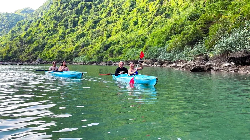 Tourists paddle blue kayaks along a limestone karst shoreline in Lan Ha Bay near Cat Ba.